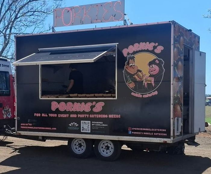 The Porkie's trailer set up at an event, hatch open and neon sign lit